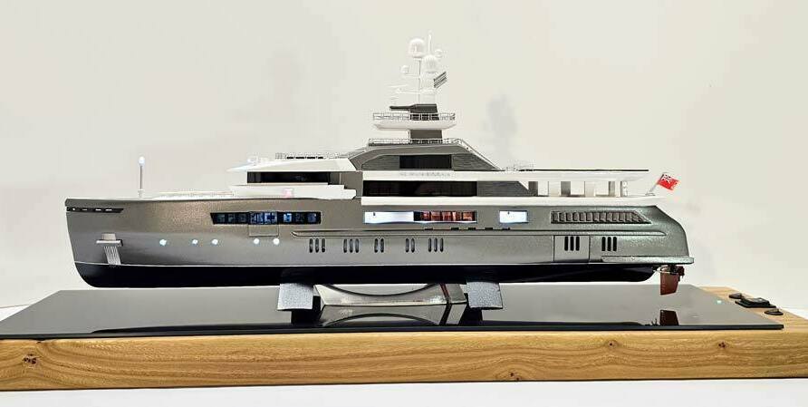 Масштабный 3D макет современной моторной яхты. Модель выполнена с высокой детализацией: видны палубы, вертолетная площадка, радиолокационная мачта, иллюминаторы и элементы корпуса. Макет установлен на деревянной подставке с глянцевой вставкой.