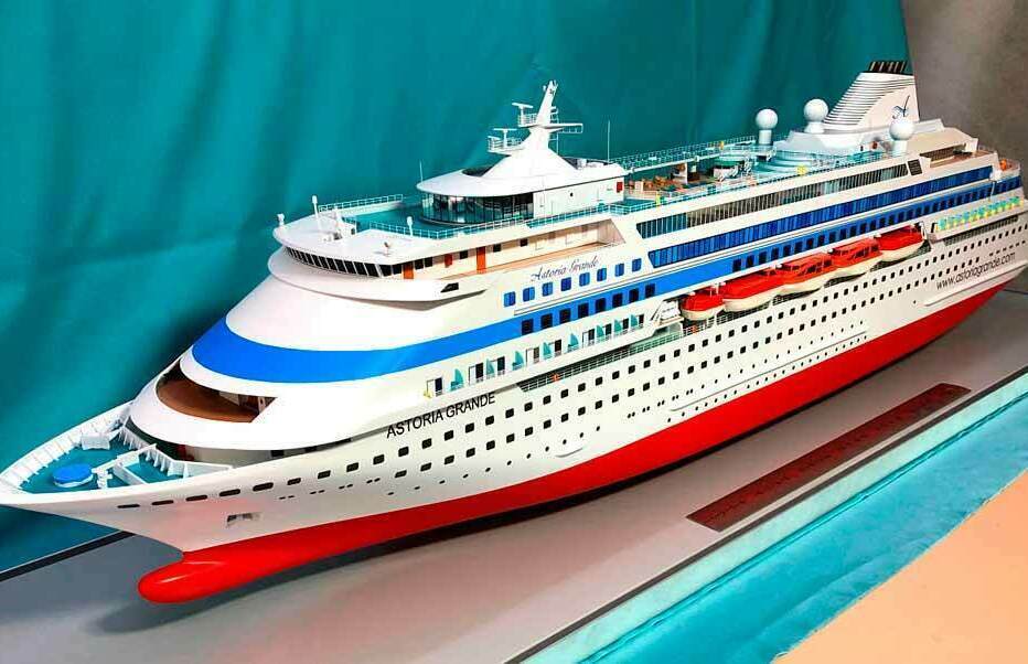 Масштабная модель круизного лайнера Astoria Grande — детализированная судомодель с палубами, спасательными шлюпками и элементами дизайна премиум-класса, воплощающая роскошь морских путешествий Детализированная масштабная модель круизного лайнера Astoria Grande, выполненная с высокой точностью. Видны несколько палуб с рядами окон кают, спасательные шлюпки, леерные ограждения, элементы верхней палубы, включая зоны отдыха и смотровые площадки. Корпус окрашен в фирменные цвета — белый с ярко-синей полосой и красной ватерлинией. Чётко различимы надписи с названием судна. Модель демонстрирует характерные черты современного круизного лайнера: обтекаемую форму носа, многоуровневую архитектуру надстроек и стильную эстетику. Идеально подходит для коллекционеров, выставочных экспозиций и оформления интерьеров, связанных с морской тематикой.