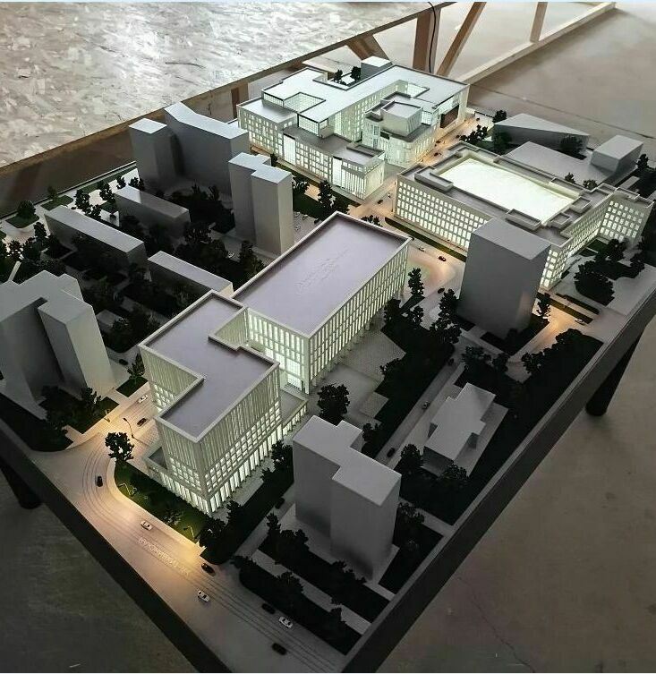 3D-масштабный макет комплекса нового кампуса МГТУ им. Н. Э. Баумана, демонстрирующий несколько многоэтажных зданий с современным архитектурным дизайном. На макете видны учебные корпуса с большими остеклёнными фасадами, жилые здания, административные постройки. Проработана инфраструктура: подъездные пути с миниатюрными автомобилями, пешеходные зоны, зелёные насаждения, внутренние дворики. Отображены элементы благоустройства — дорожки, газоны, деревья. Макет позволяет оценить планировку кампуса, расположение объектов и их взаимосвязь, а также масштаб застройки. Идеален для презентации проекта, архитектурного анализа и планирования территории.