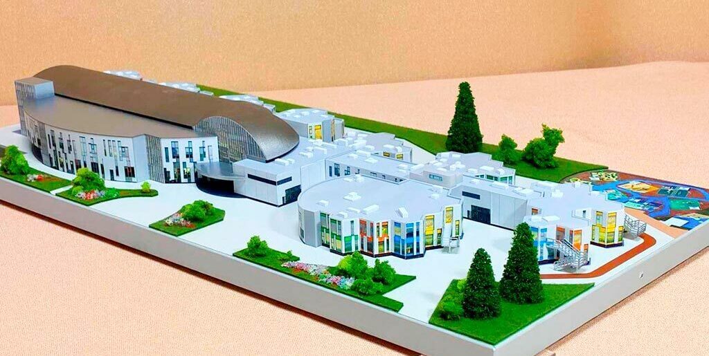 3-D масштабный архитектурный макет гимназии с модульными зданиями, купольным актовым залом, зонированной территорией и детской площадкой, изготовленный на заказ в макетной мастерской для демонстрации