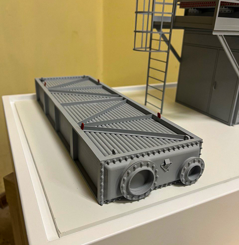 Масштабный макет паровой машины промышленного назначения: детализированная модель оборудования для выставочной презентации, изготовленная на заказ в Студии макетов — демонстрация инженерных решений в миниатюре Масштабная модель паровой машины с высокой степенью детализации: чётко видны технологические патрубки, крепёжные элементы, рёбра жёсткости и конструктивные узлы. Модель выполнена в реалистичной цветовой гамме, с имитацией металлических поверхностей. Компактная композиция включает лестничные конструкции и элементы производственного окружения, подчёркивающие индустриальный характер объекта. Идеально подходит для демонстрации на отраслевых выставках, презентациях для инвесторов и образовательных мероприятиях. Изготовлена на заказ в Студии макетов с соблюдением точных пропорций и ключевых технических особенностей реального оборудования.