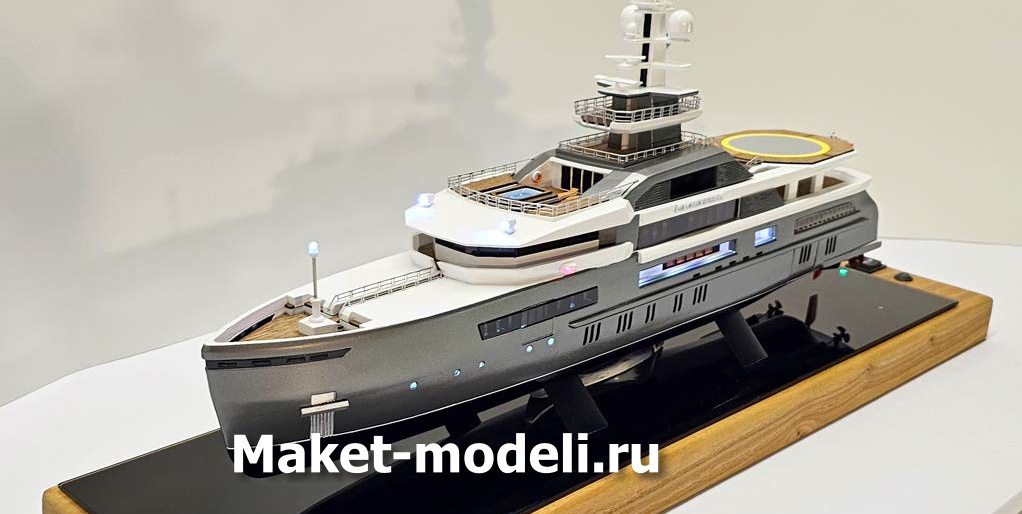Масштабный 3D макет современной моторной яхты. Модель выполнена с высокой детализацией: видны палубы, вертолетная площадка, радиолокационная мачта, иллюминаторы и элементы корпуса. Макет установлен на деревянной подставке с глянцевой вставкой.