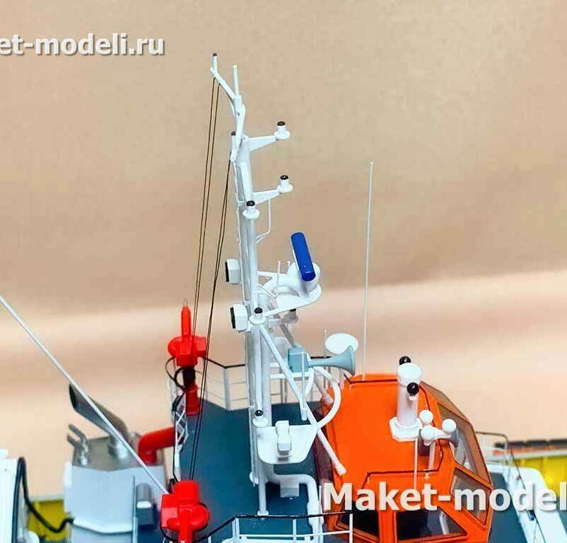 Навигационная мачта (мачтово‑антенный пост) на крыше ходовой рубки скоростного поисково‑спасательного катера типа SAR.  Что видно на модели: • Трубчатая навигационная мачта с вантами. • Открытая антенна РЛС (radar open array). • Штыревые УКВ/АИС антенны. • Спутниковая/GPS «грибковая» антенна. • Навигационные огни (топовый и дополнительный огни на рейках). • Поисковый прожектор/оптико‑электронная головка на крыше рубки. • Тифон/громкоговоритель (рупорные звуковые сигналы). • Леерное ограждение вокруг площадки и спасательный круг. • Элементы пожарного оборудования (лафетный ствол) у борта — признак аварийно‑спасательного/пожарного назначения судна.