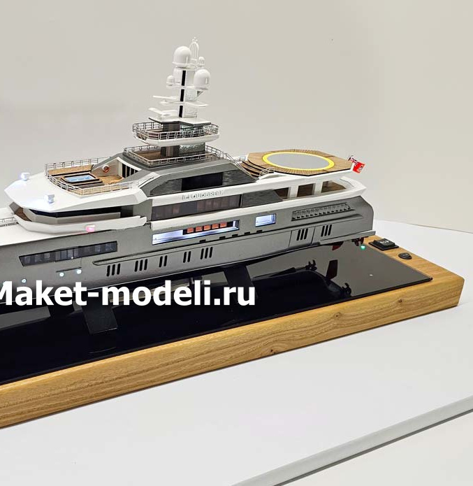 Масштабный 3D макет современной моторной яхты. Модель выполнена с высокой детализацией: видны палубы, вертолетная площадка, радиолокационная мачта, иллюминаторы и элементы корпуса. Макет установлен на деревянной подставке с глянцевой вставкой.