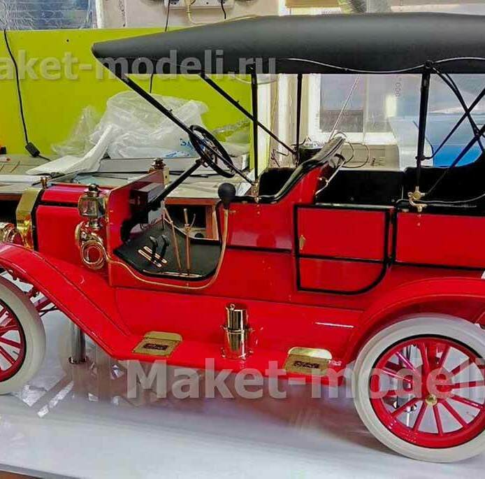 Детально проработанная масштабная модель автомобиля Ford Model T 1908 года в ярком красном цвете с чёрным тентом. Видны характерные особенности: латунные фары и декоративные накладки, рулевое колесо с кожаной оплёткой, классические белые покрышки колёс с красными спицами. Модель отличается высокой степенью детализации — от приборной панели до крепёжных элементов. Идеально подходит для музейной экспозиции или презентационного стенда, подчёркивает аутентичность и эстетику автомобильного дизайна начала XX века. Изготовлена на заказ с сохранением всех исторических пропорций и отделки.