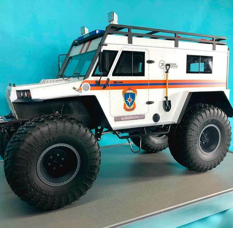 Масштабная модель вездехода Север Тракс МЧС России: детализированная копия снегоболотохода на демонстрационной подставке для выставок и презентаций, изготовленная на заказ в макетной мастерской Maket-modeli.ru Выставочный макет вездехода Sever Trucks в ливрее МЧС на огромных внедорожных колесах Nortec с экспедиционным багажником, фароискателями и шанцевым инструментом на кузове
