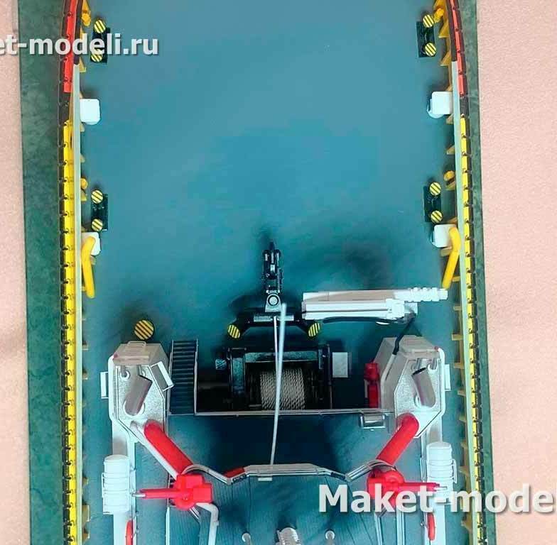 Назначение узла: обеспечение буксировки и швартовных операций; протаскивание и удержание троса в заданной плоскости, безопасная работа на кормовой палубе. • Кормовая рабочая палуба буксира. • Центрально установленная буксирная лебёдка с металлическим тросом (двухбарабанная/спулочная секция). • Проведение троса через буксирную скобу/клюз в районе кормы. • Гидравлические «челюсти» и выдвижные буксирные пины для фиксации троса на оси судна. • Небольшой палубный кран‑манипулятор для работы с такелажем. • По бортам — привальные брусья и отбойные устройства, швартовные тумбы/кнехты и клюзы с сигнальной разметкой.