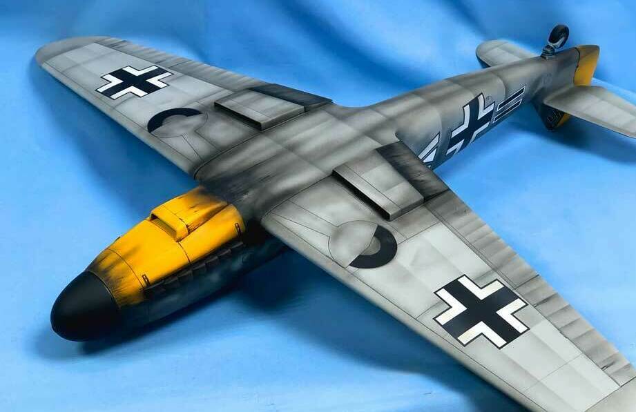 Детализированная масштабная модель немецкого истребителя Messerschmitt BF-109G-6 с характерной камуфляжной окраской и опознавательными знаками Люфтваффе: чёрными крестами на крыльях и фюзеляже, жёлтым хвостовым оперением и красно-белым знаком на носу. Реалистичная кабина пилота, проработанные элементы корпуса и шасси. Идеальный выбор для коллекционеров, музейных экспозиций и тематических диорам, посвящённых Второй мировой войне.