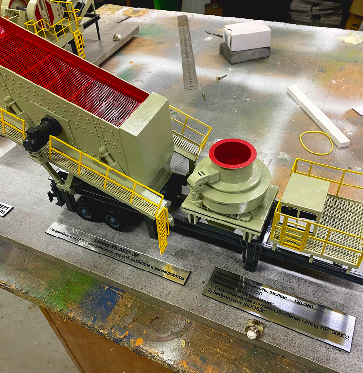 Масштабный макет транспортёра промышленного оборудования с ударной дробилкой Liming NK-9532-2K и виброгрохотом SKX1536 — выставочная модель, изготовленная на заказ в Студии макетов: детализированное отображение производственной линии Детально проработанный макет транспортёрной системы промышленного оборудования в масштабе: представлен комплекс с гидравлической ударной дробилкой Liming HPT300C2, виброгрохотом SKX1536 и транспортёрной лентой с красной решёткой. Модель включает защитные жёлтые ограждения, лестничные пролёты, опорные конструкции и шасси с колёсами, имитирующими мобильную установку. Проработаны элементы управления и сервисные площадки. Визуализирована интеграция оборудования в производственный процесс с указанием технических параметров (производительность 190–380 т/час). Идеален для демонстрации на отраслевых выставках, планирования размещения оборудования и презентации технологических решений в горнодобывающей и перерабатывающей промышленности.