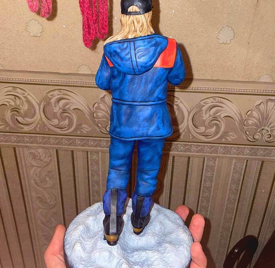 3D-фигурка человека-женщина в стиле уличного образа: кастомная статуэтка на заказ по фото, напечатанная на 3D-принтере — стильная поза с тростью, кепкой и солнцезащитными очками. Детализированная модель в сине-оранжевой куртке для коллекционеров и декора! Изготовленная для подарка Кастомная 3D-фигурка женщины, изготовленная по фотографии на 3D-принтере. Статуэтка изображает женщину в расслабленной, но выразительной позе с тростью в руке. Одета в стильную сине-оранжевую куртку, чёрную кепку, солнцезащитные очки, светлый шарф и практичные ботинки. Волосы распущены, на лице — уверенная улыбка. Фигурка установлена на круглой подставке с имитацией снежного покрытия. Пример персонализированной 3D-печати с высокой детализацией: проработаны черты лица, текстура одежды и аксессуаров. Подходит для украшения интерьера, коллекционирования или в качестве оригинального подарка.