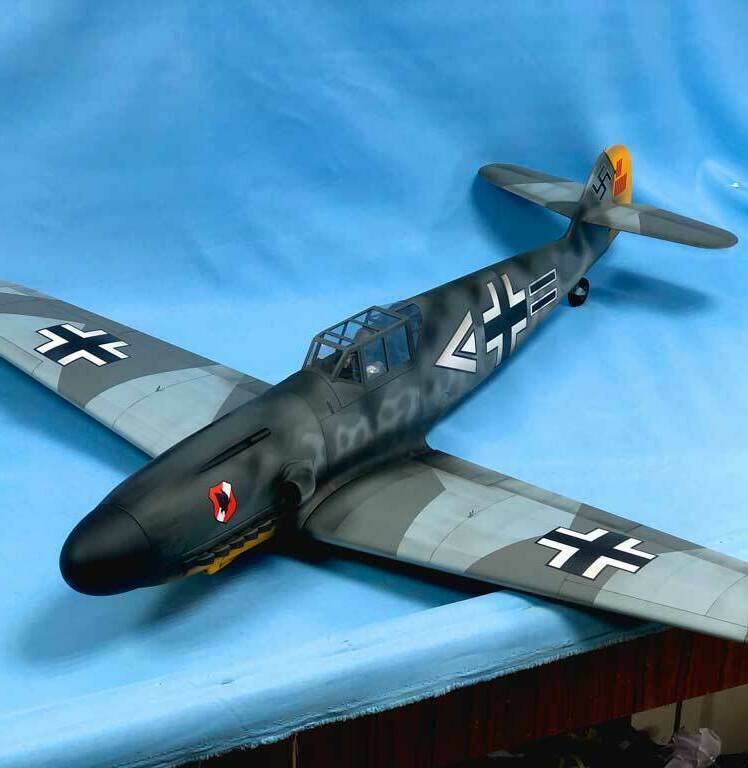Детализированная масштабная модель немецкого истребителя Messerschmitt Bf 109G с характерной камуфляжной окраской, опознавательными знаками Люфтваффе (чёрные кресты на крыльях и фюзеляже), жёлтым хвостовым оперением и красно-белым кругом на носу. Реалистичная копия исторического самолёта времён Второй мировой войны, идеально подходящая для коллекционеров, любителей авиамоделей и реконструкторов. Проработаны кабина пилота, элементы вооружения и аэродинамические детали.
