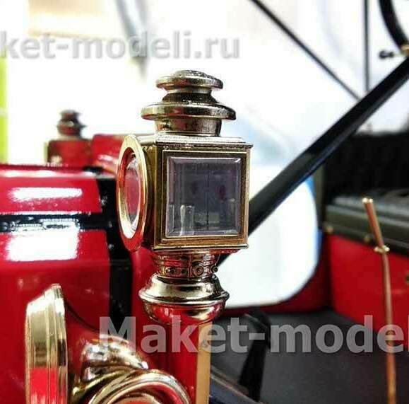 Масштабная модель ретро-автомобиля Ford Model T 1912 года в насыщенном красном цвете с чёрным кожаным салоном. В фокусе — изысканная латунная фара с прозрачным стеклом и декоративными элементами, подчёркивающая винтажный стиль. Видна часть рулевого колеса и детали интерьера, включая деревянные рычаги управления. Презентационная модель, изготовленная на заказ, идеально подойдёт для музейной экспозиции — воплощение инженерного искусства начала XX века.