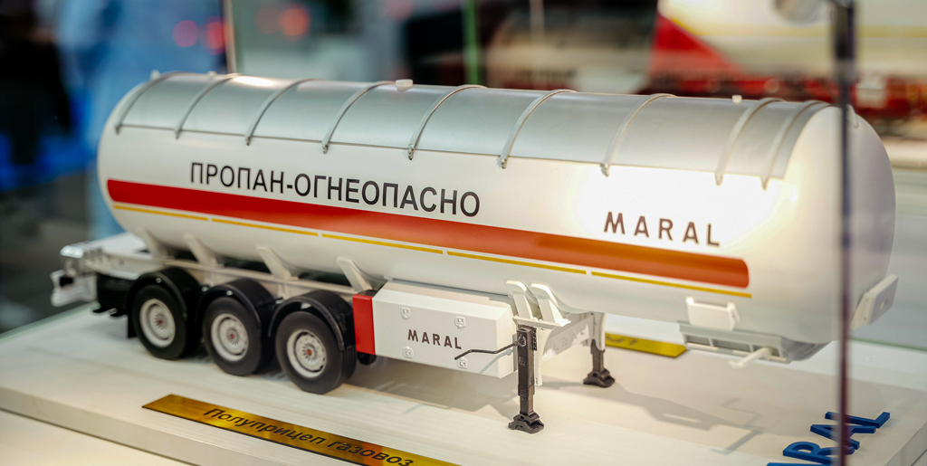 Масштабная модель цистерны для перевозки газа с надписью "ПРОПАН-ОГНЕОПАСНО" на боку. На цистерне написано "MARAL". Цистерна белого цвета с красной полосой и установлена на трехосном шасси. 