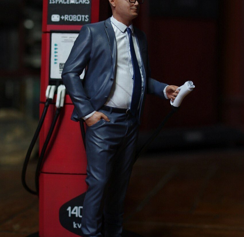 Детализированная 3D-фигурка бизнесмена у зарядной станции, изготовленная на заказ с помощью 3D-принтера — коллекционная модель с реалистичной проработкой деталей, по фото, масштабная фигурка для офиса или коллекции 3D-фигурка мужчины в деловом костюме у зарядной станции „ISPACE CARS + ROBOTS“, напечатанная на 3D-принтере по фото, с реалистичной детализацией: очки, галстук, поза с заправочным пистолетом, масштабная модель для декора офиса, 140 кВ на корпусе станции