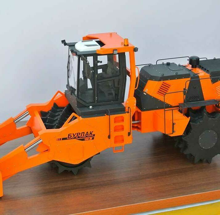 Масштабная модель спецтехники Бурлак: детализированный выставочный макет дорожного уплотнителя и бульдозера для презентаций Оранжевая масштабная копия тяжелой машины Бурлак с передним отвалом, панорамной кабиной и шипованными стальными колесами на демонстрационном стенде , изготовленная на заказ в макетной мастерской Maket-modeli.ru