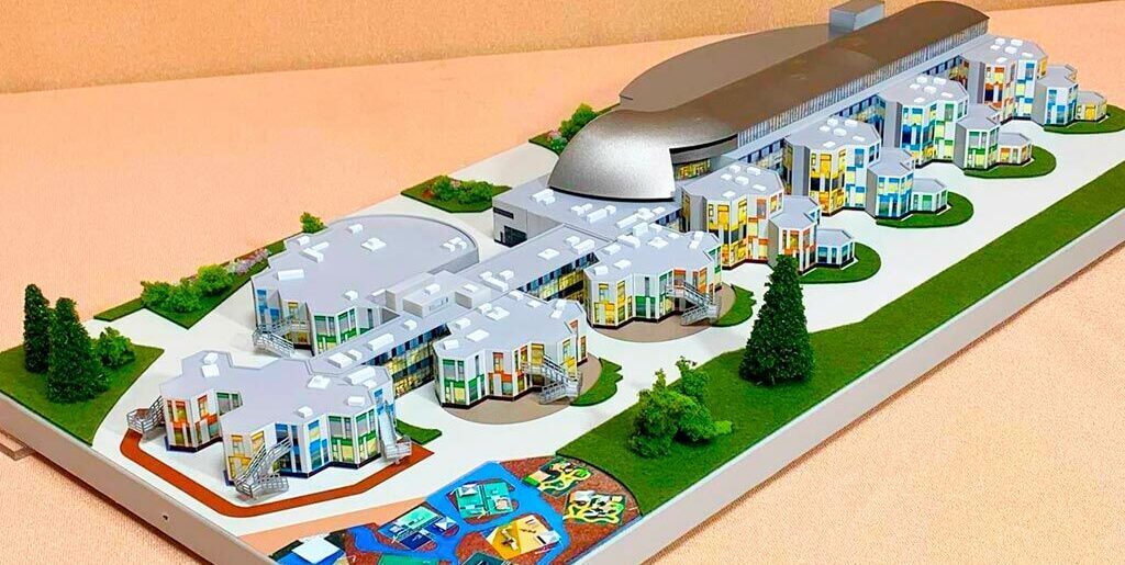 3-D масштабный архитектурный макет гимназии с модульными зданиями, купольным актовым залом, зонированной территорией и детской площадкой, изготовленный на заказ в макетной мастерской для демонстрации