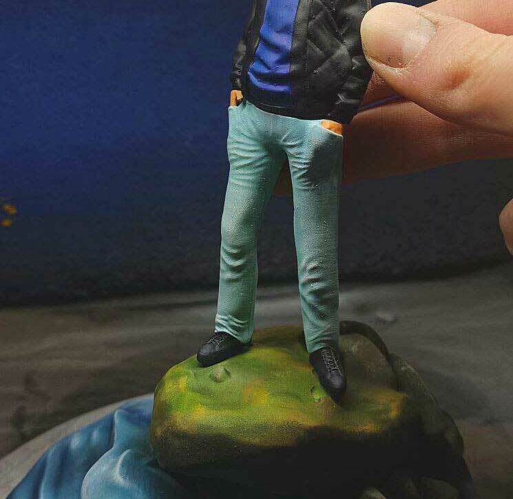 3D-фигурка человека на заказ по фото: стильный образ с солнцезащитными очками и кожаной курткой, напечатанная на 3D-принтере. Реалистичная статуэтка в расслабленной позе на декоративном основании — уникальный подарок! Реалистичная 3D-фигурка человека, изготовленная по фотографии на 3D-принтере. Статуэтка изображает мужчину в расслабленной позе, стоящего на стилизованном основании, напоминающем камень у воды. Одет в чёрную кожаную куртку поверх синего худи, светло-голубые джинсы и чёрные туфли. На лице — солнцезащитные очки, волосы аккуратно уложены. Детализированная проработка одежды, черт лица и позы придаёт фигурке максимальную реалистичность. Подходит для коллекционирования, украшения интерьера или в качестве персонализированного подарка. Пример качественной 3D-печати с последующей ручной отделкой.