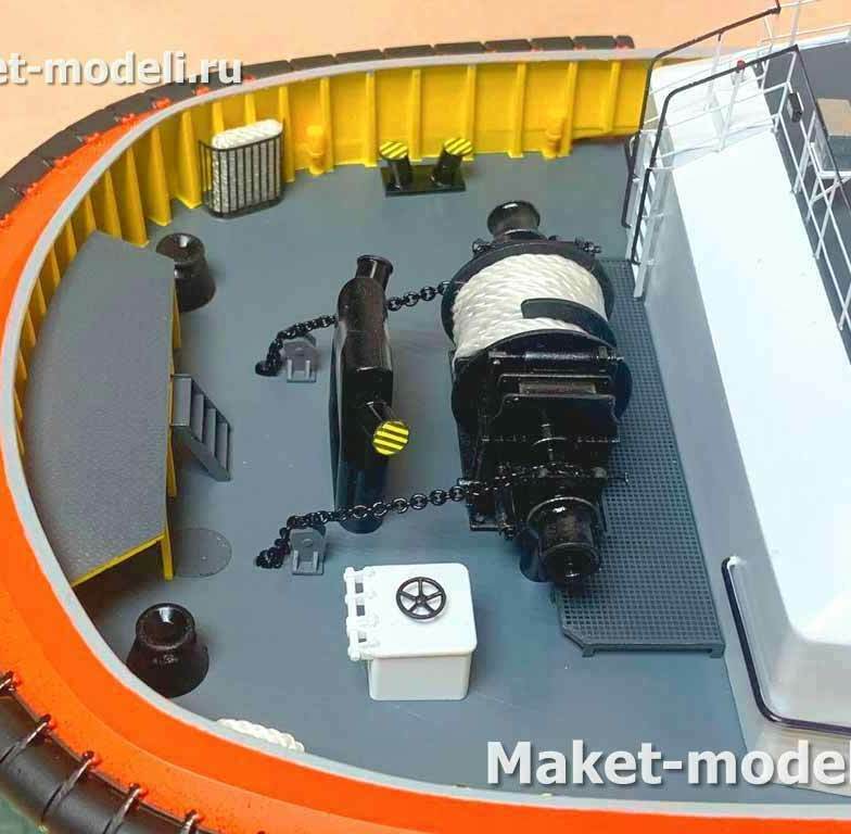 • Буксирная лебёдка с намотанным синтетическим буксирным тросом на барабане, с тормозом и приводом (гидро/электро). Рядом противоскользящая площадка для работы матросов.   • Быстросбрасываемый буксирный крюк/сцепное устройство (QRH) в центре, со страховочными цепями и сигнальной окраской.   • Швартовные кнехты/тумбы и направляющие (клюзы/фэйрлиды) для заводки и крепления концов.   • Пульт локального управления лебёдкой/крюком.   • Леерные ограждения и палубные настилы.   • По периметру — массивный резиновый фендер для работы “в упор”.  • Лебёдка обеспечивает выборку/травление и поддержание нужного натяжения буксирного троса при буксировке и эскорте, позволяет быстро отдавать или выбирать линию под нагрузкой.   • Быстросбрасываемый крюк — аварийный сброс буксирного троса при перегрузке или риске опрокидывания (girting), повышает безопасность.   • Кнехты, клюзы и направляющие — безопасное ведение и крепление швартовых/буксирных линий без перетирания.   • Фендер защищает корпус при толкании и прижиме к борту буксируемого судна или причалу.  Такой макет необходим для:  Демонстрация компоновки буксирно‑швартовного устройства (БШУ) заказчику, обучение персонала, согласование эргономики и зон обслуживания, а также выставочная/презентационная модель.