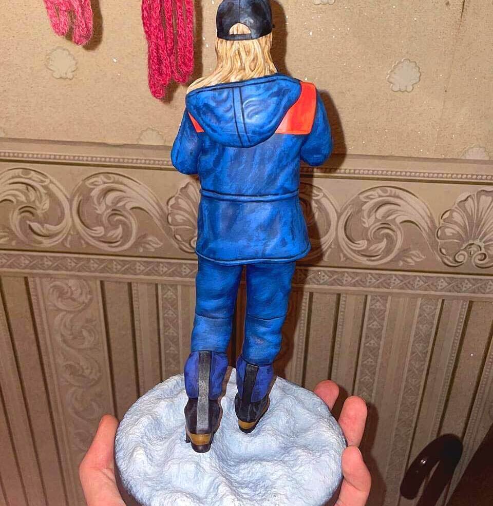 3D-фигурка человека-женщина в стиле уличного образа: кастомная статуэтка на заказ по фото, напечатанная на 3D-принтере — стильная поза с тростью, кепкой и солнцезащитными очками. Детализированная модель в сине-оранжевой куртке для коллекционеров и декора! Изготовленная для подарка Кастомная 3D-фигурка женщины, изготовленная по фотографии на 3D-принтере. Статуэтка изображает женщину в расслабленной, но выразительной позе с тростью в руке. Одета в стильную сине-оранжевую куртку, чёрную кепку, солнцезащитные очки, светлый шарф и практичные ботинки. Волосы распущены, на лице — уверенная улыбка. Фигурка установлена на круглой подставке с имитацией снежного покрытия. Пример персонализированной 3D-печати с высокой детализацией: проработаны черты лица, текстура одежды и аксессуаров. Подходит для украшения интерьера, коллекционирования или в качестве оригинального подарка.