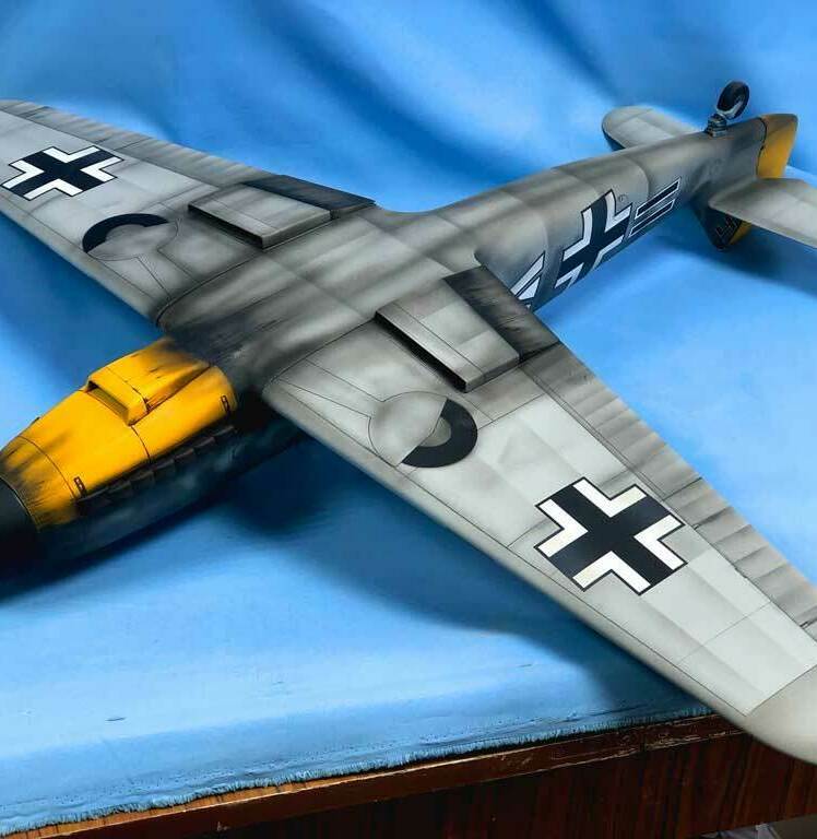 Детализированная масштабная модель немецкого истребителя Messerschmitt Bf 109G с характерной камуфляжной окраской, опознавательными знаками Люфтваффе (чёрные кресты на крыльях и фюзеляже), жёлтым хвостовым оперением и красно-белым кругом на носу. Реалистичная копия исторического самолёта времён Второй мировой войны, идеально подходящая для коллекционеров, любителей авиамоделей и реконструкторов. Проработаны кабина пилота, элементы вооружения и аэродинамические детали.