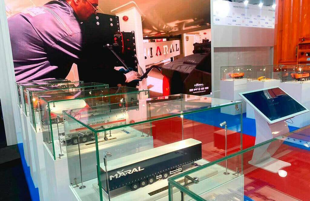 Экспозиция промышленных моделей на выставке: макеты грузовых автомобилей MARAL и спецтехники — инновации в производстве, изготовленные на заказ в макетной мастерской Maket-modeli.ru Выставка с детализированными макетами грузовой техники MARAL и промышленного оборудования на выставочном стенде. Демонстрация достижений в сфере металлообработки и производства транспортных средств: модели автоцистерн и полуприцепов в стеклянных витринах, дополненные интерактивным экраном и рекламным баннером с изображением специалиста за работой.