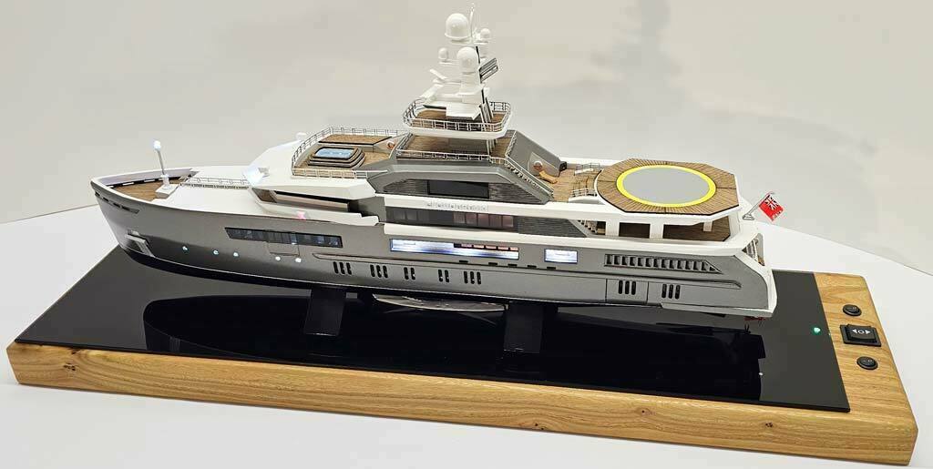 Масштабный 3D макет современной моторной яхты. Модель выполнена с высокой детализацией: видны палубы, вертолетная площадка, радиолокационная мачта, иллюминаторы и элементы корпуса. Макет установлен на деревянной подставке с глянцевой вставкой.