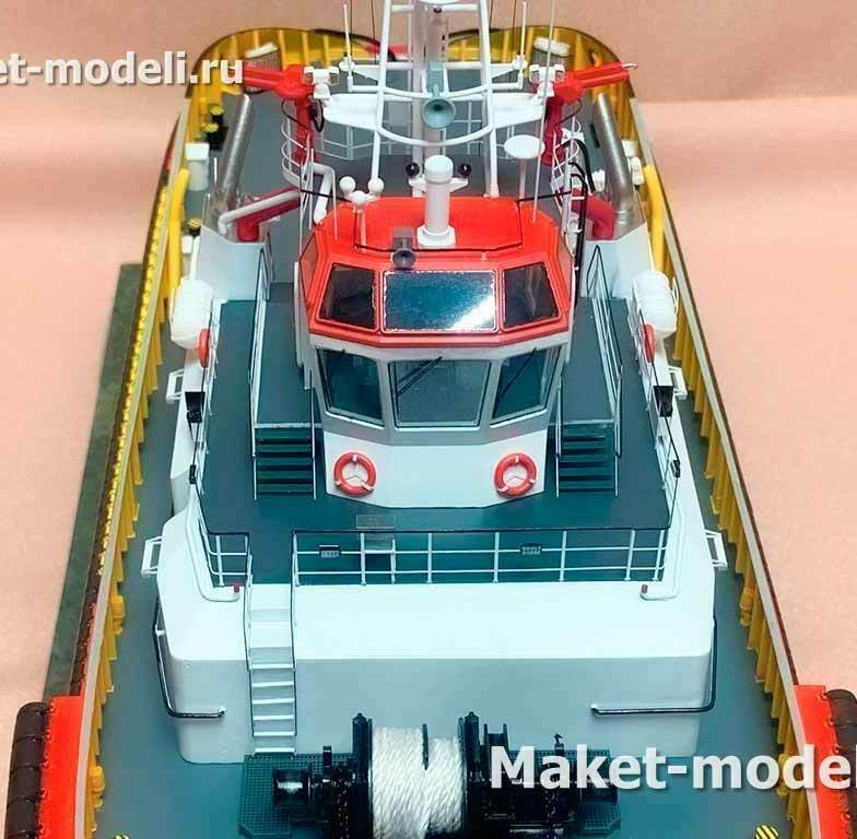 • Носовая часть судна с надстройкой и ходовой рубкой панорамного обзора. • Мачта с антеннами и навигационными огнями; прожекторы и громкоговоритель. • Два лафетных ствола (пожарные мониторы) по бортам рубки. • Носовой буксирный лебёдочный пост с тросом; швартовные кнехты. • Палубные леера, трапы, спасательные круги. • Высокий борт с противоударным фендерным поясом.  Назначение модели: демонстрация компоновки и оснащения портового буксира для буксировки, эскортирования и аварийно-спасательных/пожарных работ в акватории порта.