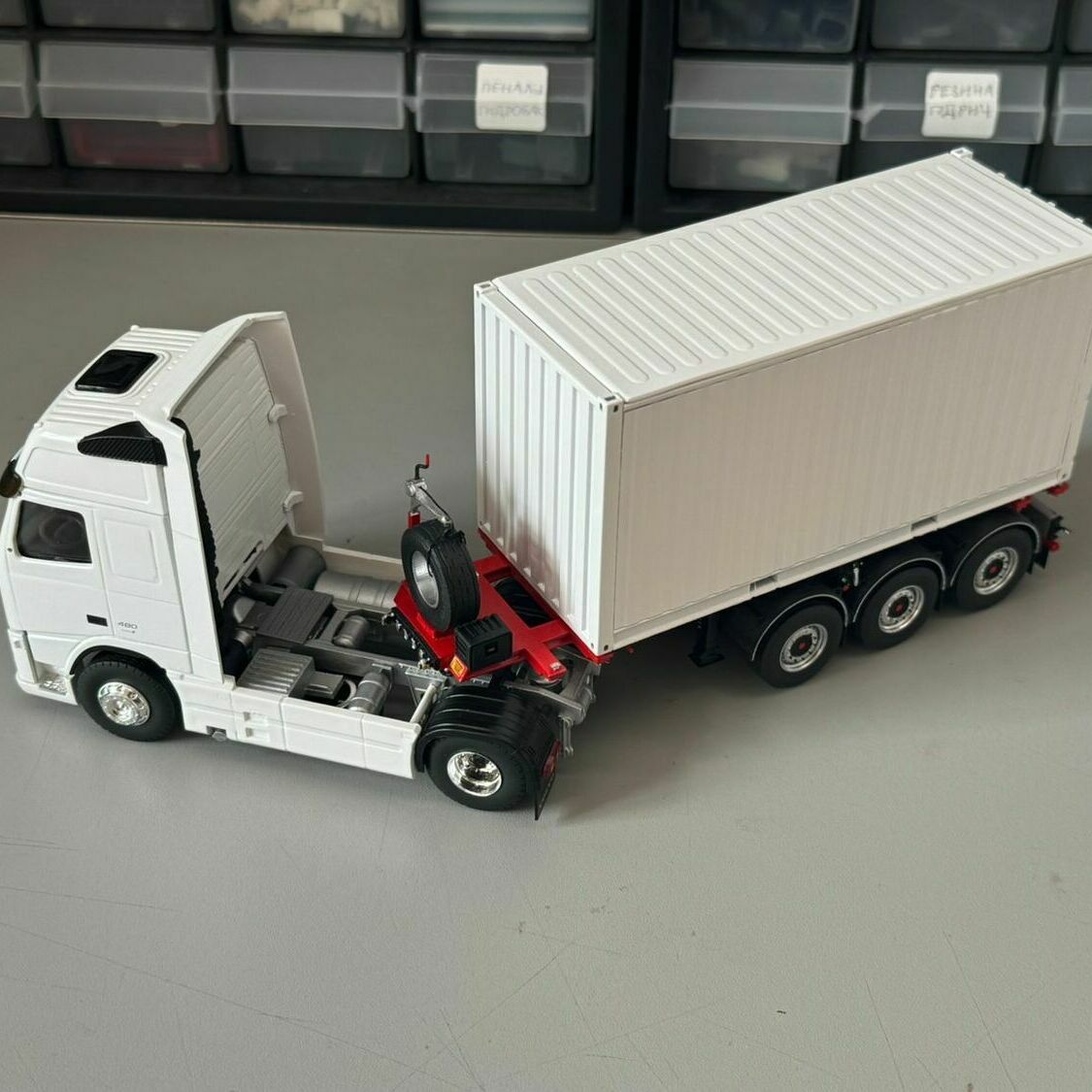 Модель грузовика тягача с прицепом Масштабная модель белого седельного тягача с трехосным полуприцепом и контейнером крупным планом на рабочем столе изготовленный на заказ для выставки в г. Москва