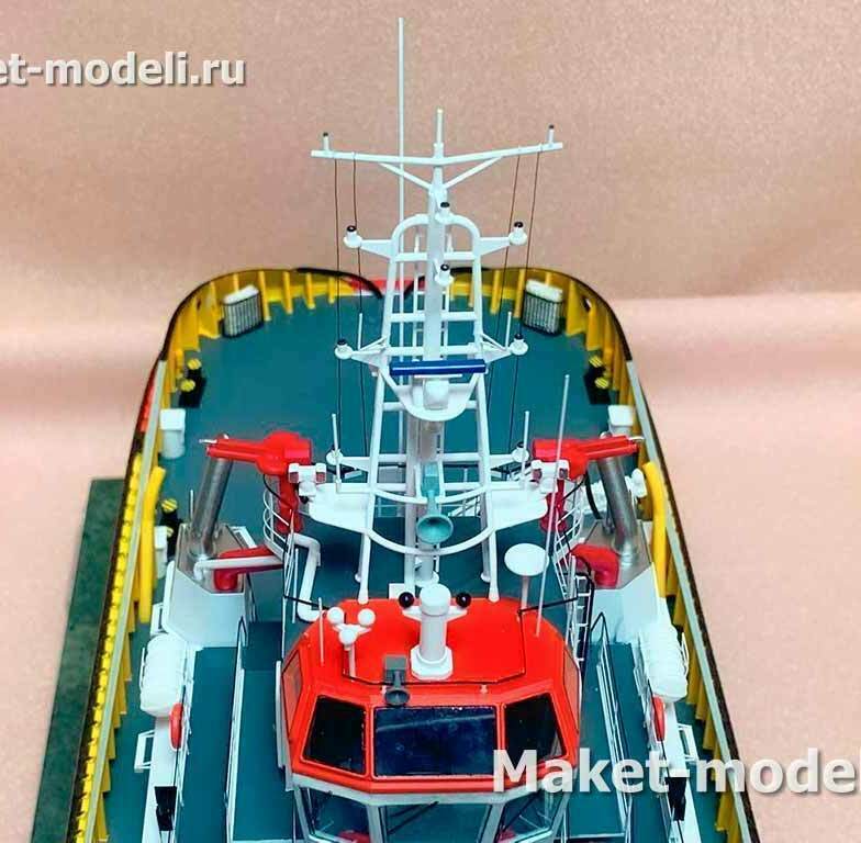 • Ходовой мостик с остеклением и крышей с прожектором/сигнальными огнями. • Мачта связи и навигации: кронштейны под РЛС X/S‑диапазона, спутниковые/GPS и AIS‑антенны, УКВ‑штыревые антенны, топовые и бортовые огни, звуковой сигнал. • Два красных пожарных монитора (водяные/пенно-водяные лафетные стволы) по бортам. • Выпуски выхлопов, леерное ограждение, кнехты и швартовные тумбы, защищённый борт с фендерным поясом/коушами.  • Масштабный демонстрационный макет портового буксира с пожарным оборудованием класса FiFi (Fire Fighting), либо «спасательно-буксирное судно портового флота».  Для чего это нужно • Презентация проекта и маркетинг: показ компоновки, оснащения и уровня детализации заказчику/на выставках. • Предпроектная и конструкторская отработка: проверка видимости с мостика, размещения антенн, мониторов, огней и путей эвакуации. • Обучение и брифинг персонала: знакомство с расположением навигационных и пожарных систем. • Музейный/выставочный экспонат или представительский подарок верфи/заказчику.  Назначение реального прототипа • Буксировка и швартовка судов в акватории порта, аварийно-спасательные работы и тушение пожаров на судах и причалах с подачей воды/пены через лафетные стволы; навигация и связь обеспечиваются комплектом РЛС и антенн на мачте.