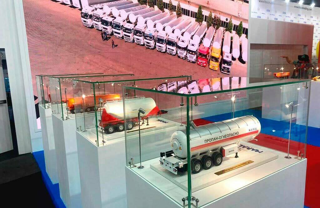 Экспозиция промышленных моделей на выставке: макеты грузовых автомобилей MARAL и спецтехники — инновации в производстве, изготовленные на заказ в макетной мастерской Maket-modeli.ru Выставка с детализированными макетами грузовой техники MARAL и промышленного оборудования на выставочном стенде. Демонстрация достижений в сфере металлообработки и производства транспортных средств: модели автоцистерн и полуприцепов в стеклянных витринах, дополненные интерактивным экраном и рекламным баннером с изображением специалиста за работой.