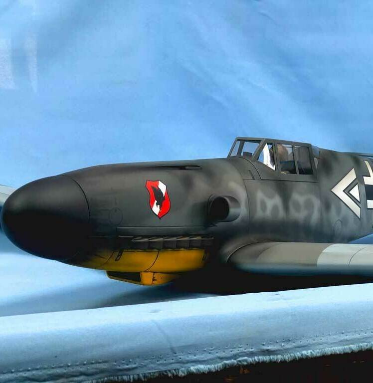 Детализированная масштабная модель немецкого истребителя Messerschmitt Bf 109G с характерной камуфляжной окраской, опознавательными знаками Люфтваффе (чёрные кресты на крыльях и фюзеляже), жёлтым хвостовым оперением и красно-белым кругом на носу. Реалистичная копия исторического самолёта времён Второй мировой войны, идеально подходящая для коллекционеров, любителей авиамоделей и реконструкторов. Проработаны кабина пилота, элементы вооружения и аэродинамические детали.