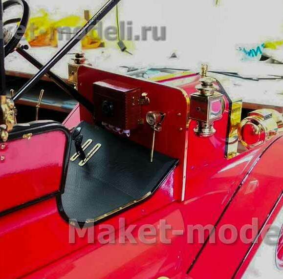 Детально проработанная масштабная модель старинного автомобиля в насыщенном красном цвете с контрастными чёрными элементами салона. Видны характерные особенности: латунные фары и декоративные детали, выразительные колёсные диски с красными спицами и белыми покрышками, рулевое колесо с кожаной оплёткой. Модель отличается высокой степенью детализации — от приборной панели до мелких крепёжных элементов. Идеальный экспонат для музея или презентационного стенда, подчёркивающий эстетику автомобильного дизайна начала XX века. Изготовлена на заказ с соблюдением исторических пропорций и отделки.