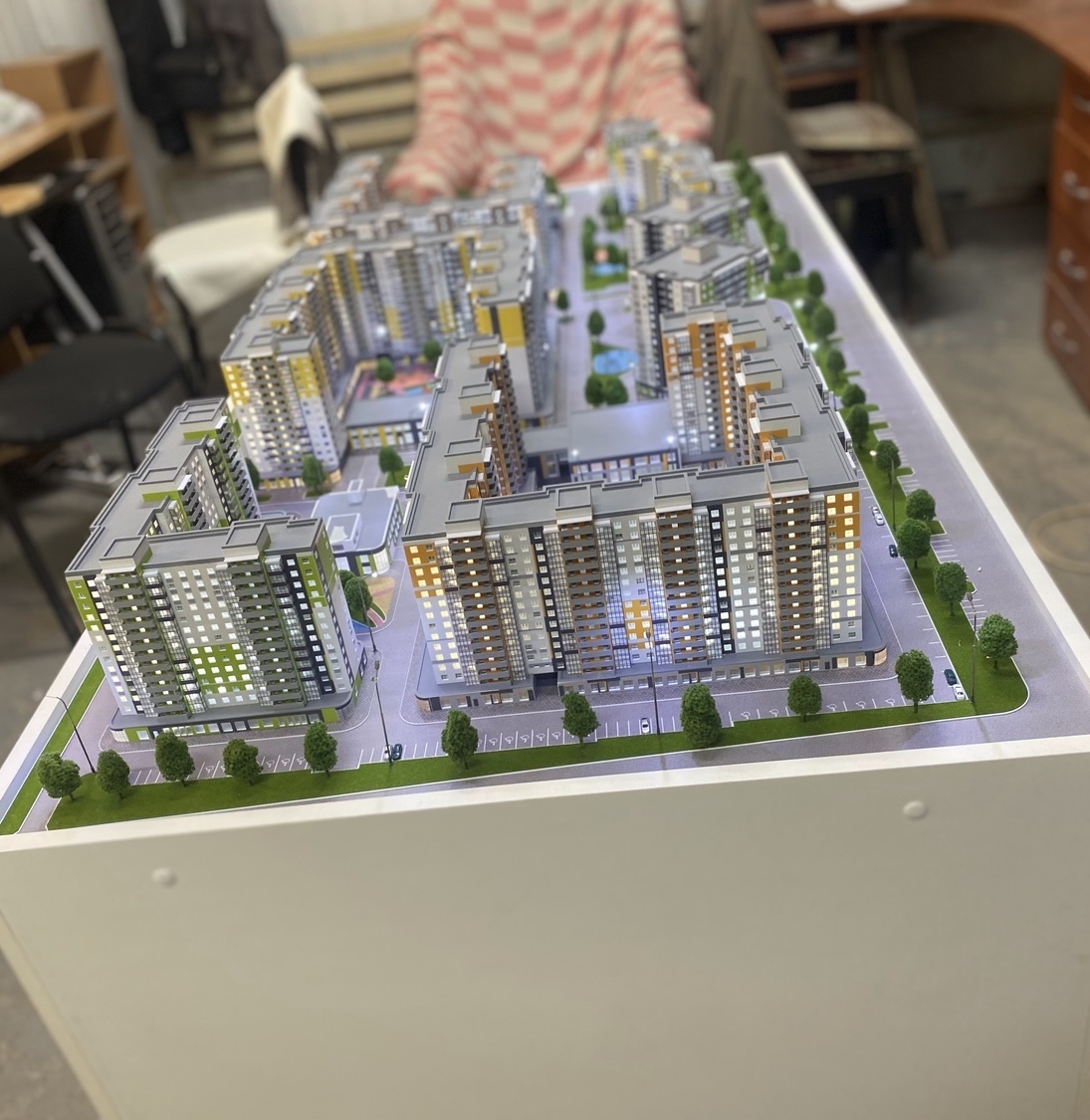 Детализированный архитектурный макет жилого комплекса с многоэтажными домами — изготовлен на заказ в макетной мастерской. Современный дизайн, разнообразие фасадов, благоустроенная территория с паркингом и зелёными насаждениями Архитектурный макет современного жилого комплекса: несколько многоэтажных зданий с разноцветными фасадами, расположенных компактно. На макете видны парковочные места, аккуратные дорожки, миниатюрные деревья и элементы благоустройства. Демонстрационная модель для презентации проекта застройки, позволяющая оценить планировку и дизайн будущего жилого района.