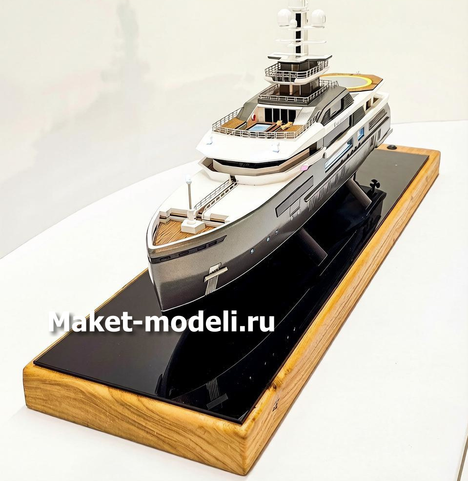 Масштабный 3D макет современной моторной яхты. Модель выполнена с высокой детализацией: видны палубы, вертолетная площадка, радиолокационная мачта, иллюминаторы и элементы корпуса. Макет установлен на деревянной подставке с глянцевой вставкой.