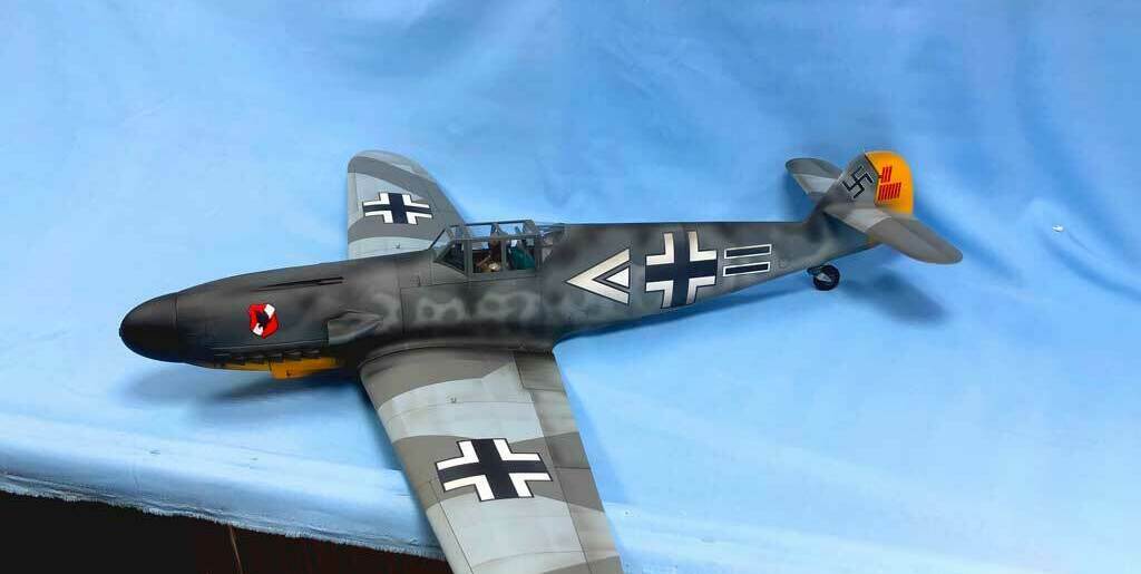 Детализированная масштабная модель немецкого истребителя Messerschmitt Bf 109G с характерной камуфляжной окраской, опознавательными знаками Люфтваффе (чёрные кресты на крыльях и фюзеляже), жёлтым хвостовым оперением и красно-белым кругом на носу. Реалистичная копия исторического самолёта времён Второй мировой войны, идеально подходящая для коллекционеров, любителей авиамоделей и реконструкторов. Проработаны кабина пилота, элементы вооружения и аэродинамические детали.