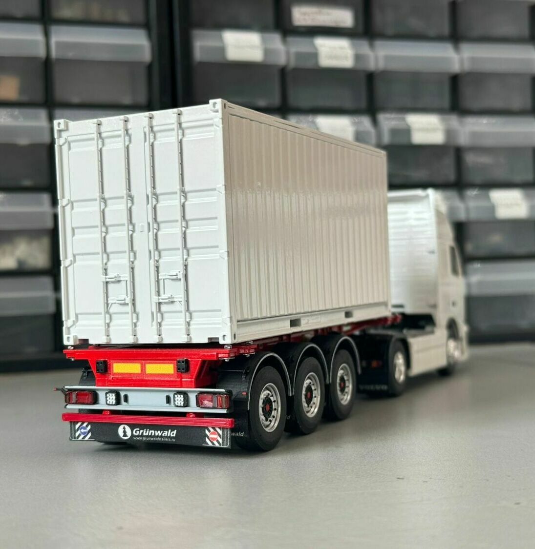 Александр Александр ⭐  image Опиши фото модели тягача volvo, что на нём изображено, дай название техническим языком    Chat AI  GPT-4.1 Сегодня На фото изображена масштабная модель магистрального седельного тягача Volvo серии FH с полуприцепом.  Техническим языком композицию можно назвать так:    «Масштабная модель магистрального седельного тягача Volvo FH 480, колесная формула 4×2, с трехосным полуприцепом-фургоном (контейнеровозом)».  Что видно на снимке: • Тягач капотнойless компоновки с высокой спальней кабиной (high-roof sleeper cab).   • Передняя светотехника: основные фары, блок дополнительных противотуманных/дальнобойных фар на переднем бампере.   • Солнечный козырёк над ветровым стеклом, сигнальные огни на крыше кабины.   • Фирменная решётка радиатора Volvo с логотипом и обозначением модели FH и мощности «480».   • Смоделированные элементы ходовой части: односкатные шины на управляемой передней оси и ведущей задней.   • Сцепка с трёхосным полуприцепом прямоугольного сечения (контейнер/фургон).    Модель установлена на ровной поверхности, на фоне стеллажей с ячейками для хранения и коробок с другими моделями. Александр Александр ⭐  image Опиши фото модели тягача volvo, что на нём изображено, дай название техническим языком    Chat AI  GPT-5.1 Сегодня На фото показана масштабная модель магистрального автопоезда:  Техническое наименование:   «Масштабная модель магистрального седельного тягача Volvo с односкатным задним мостом, агрегатированного с трёхосным полуприцепом‑контейнеровозом под морской контейнер».  Изображено: • белый седельный тягач Volvo с высокими кабиной и задней стенкой,   • седельно-сцепное устройство (седло) на раме тягача,   • смонтированное на полуприцепе запасное колесо,   • трёхосный полуприцеп красного цвета,   • установленный на полуприцепе белый прямоугольный контейнер (имитация стандартного морского/интермодального контейнера).   Фон — стеллаж с пластиковыми ячейками, что подчёркивает, что это именно коллекционная/масштабная модель, а не реальный автопоезд. Александр Александр ⭐  image Опиши фото макета или модели, что на нём изображено, дай название техническим языком и для чего и зачем это нужно.    Chat AI  GPT-5.1 Сегодня На фото показан уменьшенный макет седельного автопоезда с полуприцепом‑контейнеровозом, загруженным универсальным крупнотоннажным контейнером.  Что именно изображено технически: • Седельный тягач (белая кабина спереди, частично видна). • Трёхосный полуприцеп‑контейнеровоз (рама красного цвета, три оси с сдвоенными шинами). • Универсальный стальной контейнер ISO (типовой морской/железнодорожный контейнер с двустворчатыми дверями). • Сзади полуприцепа видны:   • светотехника (габаритные/стоп‑огни, указатели поворота, подсветка номера),   • светоотражающие элементы,   • противооткатный брус (задний защитный брус),   • грязезащитные щитки.  Для чего и зачем это нужно (в реальном прототипе): • Такой автопоезд предназначен для контейнерных перевозок в системе интермодальной логистики: «порт – железная дорога – автотранспорт – склад/клиент». • Контейнер обеспечивает:   • быструю перегрузку без перекладки товара (контейнер просто переставляют с судна на жд-платформу или автоприцеп),   • защиту груза от погодных условий и хищений,   • унификацию размеров и креплений, что упрощает планирование перевозок и складскую логистику.