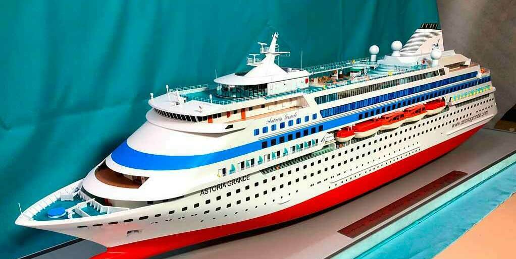 На фото изображён макет круизного лайнера под названием "Astoria Grande". Это детализированная модель, которая может быть использована для различных целей:  Название:  Макет круизного лайнера "Astoria Grande".  Описание: • Модель выполнена в масштабе, позволяющем детально воспроизвести элементы конструкции и дизайна. • Структура: Включает палубы, спасательные шлюпки, антенны и другие элементы, характерные для круизных судов. • Материалы: Обычно такие модели изготавливаются из пластика или дерева с использованием красок для достижения реалистичного вида.  Назначение: 1. Учебные цели: Используется в образовательных учреждениях для изучения морской архитектуры и судостроения. 2. Демонстрация: Может служить на выставках или в музеях для демонстрации дизайна и технологий круизных лайнеров. 3. Промоция: Используется компаниями для маркетинга и привлечения клиентов к круизным путешествиям. 4. Коллекционирование: Интересует коллекционеров моделей кораблей.  Такой макет помогает лучше понять конструкцию и функциональность реального судна, а также служит визуальным инструментом для представления концепций в морской индустрии.