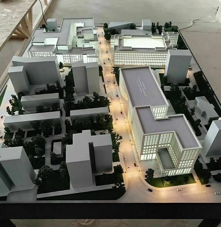 3D-масштабный макет комплекса нового кампуса МГТУ им. Н. Э. Баумана, демонстрирующий несколько многоэтажных зданий с современным архитектурным дизайном. На макете видны учебные корпуса с большими остеклёнными фасадами, жилые здания, административные постройки. Проработана инфраструктура: подъездные пути с миниатюрными автомобилями, пешеходные зоны, зелёные насаждения, внутренние дворики. Отображены элементы благоустройства — дорожки, газоны, деревья. Макет позволяет оценить планировку кампуса, расположение объектов и их взаимосвязь, а также масштаб застройки. Идеален для презентации проекта, архитектурного анализа и планирования территории.
