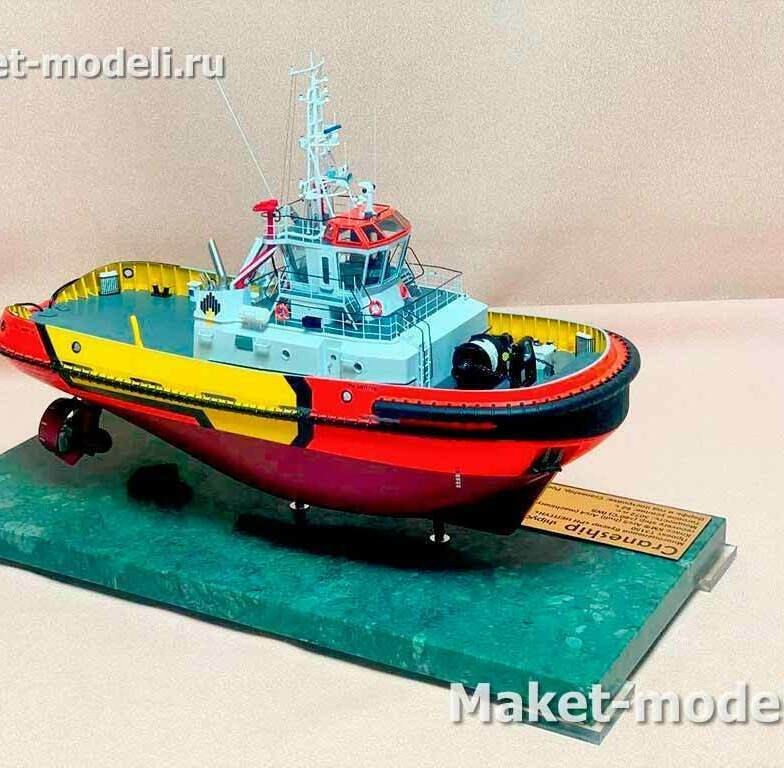 Масштабная модель судна буксира - витринный макет (в кожухе из оргстекла) многоцелевого портового судна обеспечения. По архитектуре и оснащению это малый портовый буксир с палубным краном-манипулятором. Модель многоцелевого портового буксира с палубным краном. • Стальной однопалубный корпус с мощным бортовым резиновым фендером и «пуш‑коленями» на носу — для швартовно-буксирных операций. • Приподнятая надстройка с ходовой рубкой, мачтой с РЛС, антеннами и прожекторами. • Открытая рабочая палуба на корме, оборудованная швартовными тумбами и кнехтами; установлен складной гидравлический кран-манипулятор. • Кормовая одновинтовая движительная установка с рулевым устройством (виден гребной винт и перо руля). • Окраска и маркировка заказчика («Роснефть»), что указывает на использование в составе флота обеспечения нефтяных терминалов.