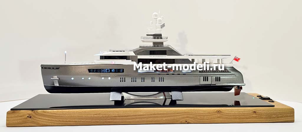 Масштабный 3D макет современной моторной яхты. Модель выполнена с высокой детализацией: видны палубы, вертолетная площадка, радиолокационная мачта, иллюминаторы и элементы корпуса. Макет установлен на деревянной подставке с глянцевой вставкой.
