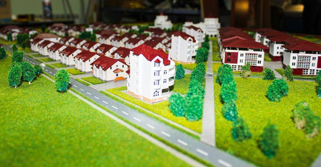 3D-масштабный макет современного многоэтажного жилого дома с детализированной инфраструктурой и озеленением — инструмент визуализации архитектурного проекта 3D-масштабный макет многоэтажного жилого здания с подсветкой фасадов, парковкой, миниатюрными моделями автомобилей, зелёными насаждениями и элементами благоустройства. Реалистичная визуализация архитектурного проекта в уменьшенном масштабе, демонстрирующая планировку двора, организацию парковочных мест и ландшафтный дизайн. Идеально для презентации инвесторам и будущим жильцам.