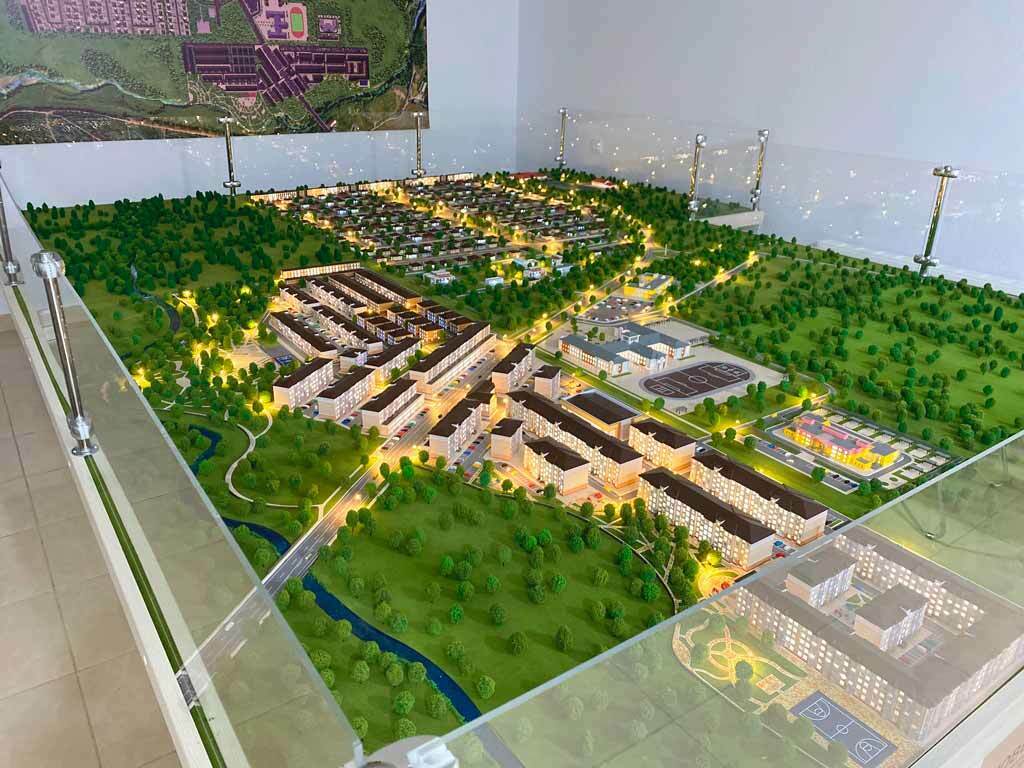 Детализированный макет микрорайона — 3D макет жилого комплекса с подсветкой: многоэтажные жилые дома и торговые секции, парковочные места, подъездные проезды, тротуары и пешеходные зоны, озеленение и деревья, рекреационные и спортивные площадки, планировка генплана и элементы благоустройства для демонстрации проектной документации и инвест презентации