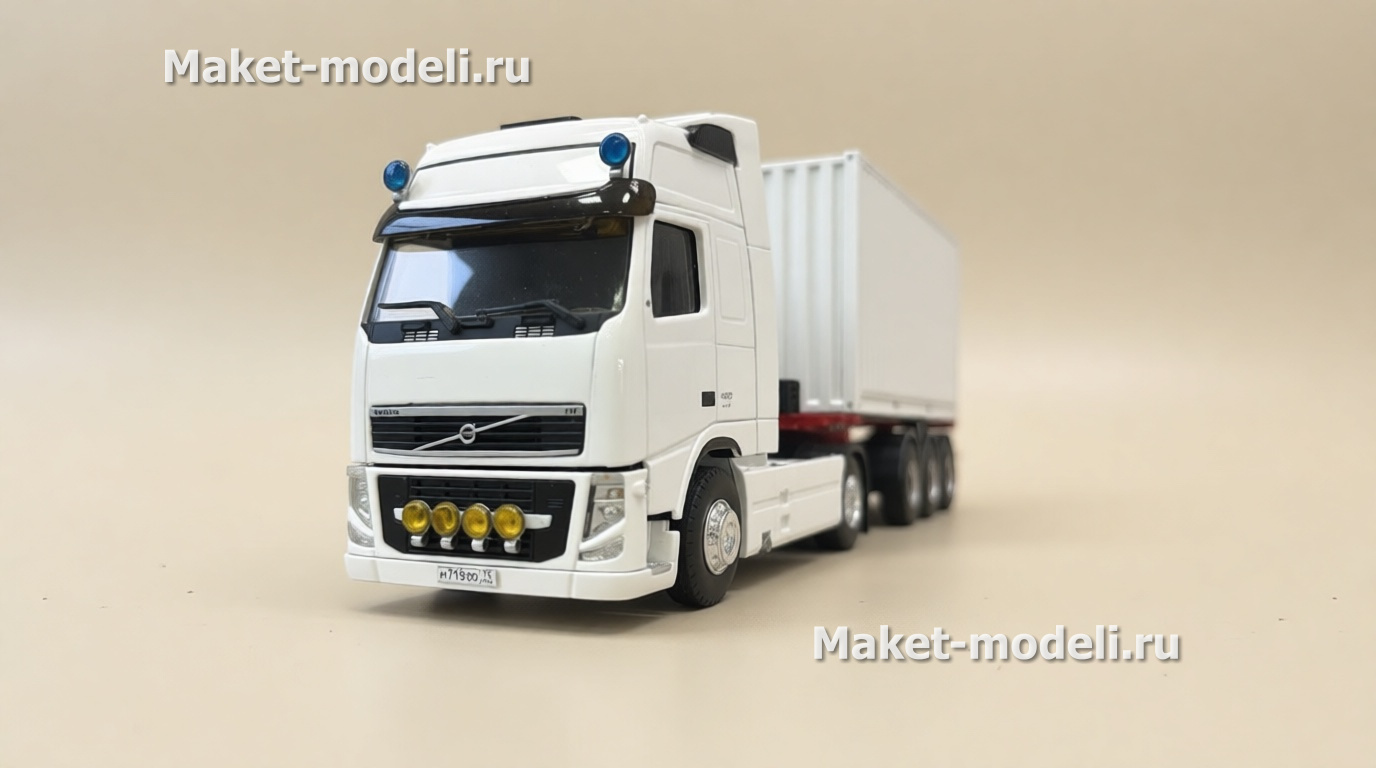 Масштабная модель магистрального седельного тягача Volvo FH 480, колесная формула 4×2, с трехосным полуприцепом-фургоном (контейнеровозом) Тягач компоновки с высокой спальной кабиной (high-roof sleeper cab). • Передняя светотехника: основные фары, блок дополнительных противотуманных/дальнобойных фар на переднем бампере. • Солнечный козырёк над ветровым стеклом, сигнальные огни на крыше кабины. • Фирменная решётка радиатора Volvo с логотипом и обозначением модели FH и мощности «480». • Смоделированные элементы ходовой части: односкатные шины на управляемой передней оси и ведущей задней. • Сцепка с трёхосным полуприцепом прямоугольного сечения (контейнер/фургон). Модель установлена на ровной поверхности, на фоне стеллажей с ячейками для хранения и коробок с другими моделями.